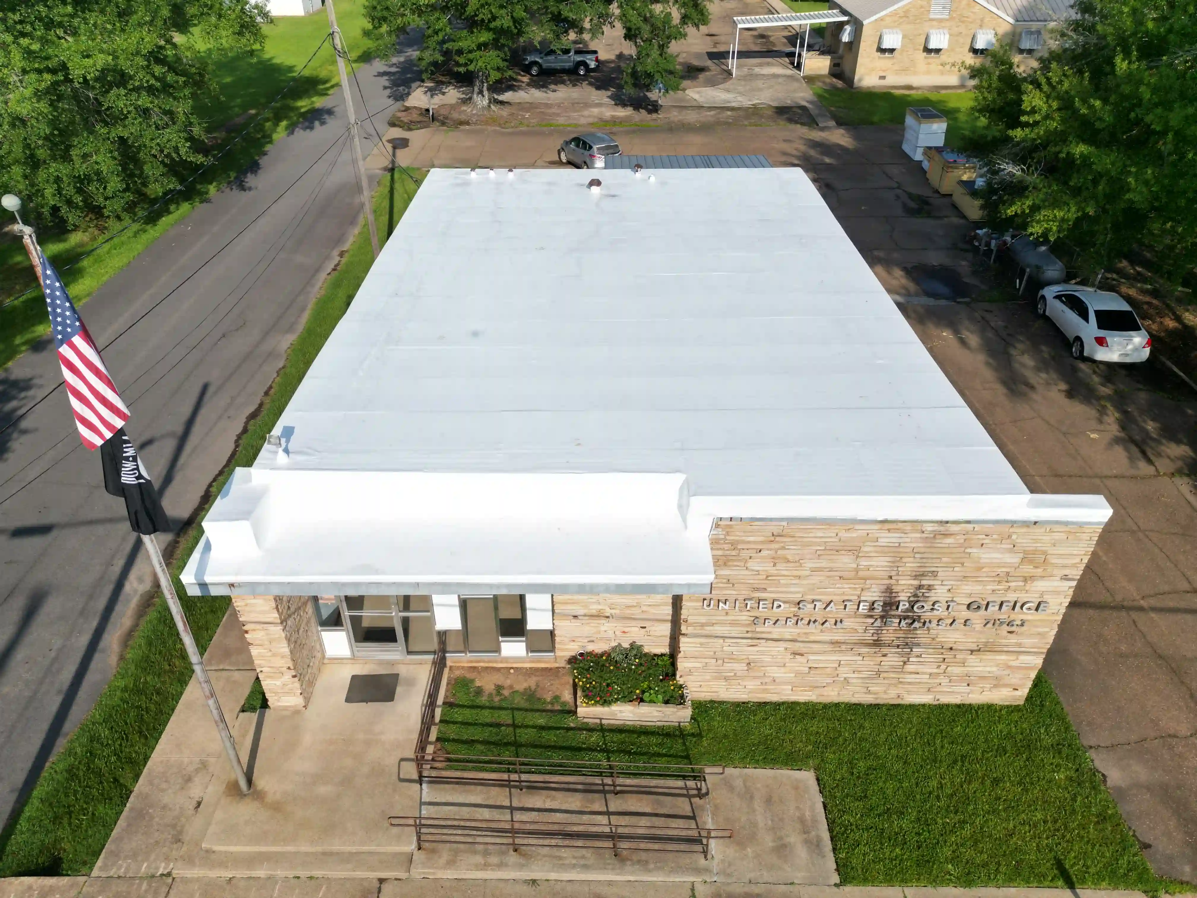 Aerial view of a stone-front public building topped with a newly replaced white membrane roof